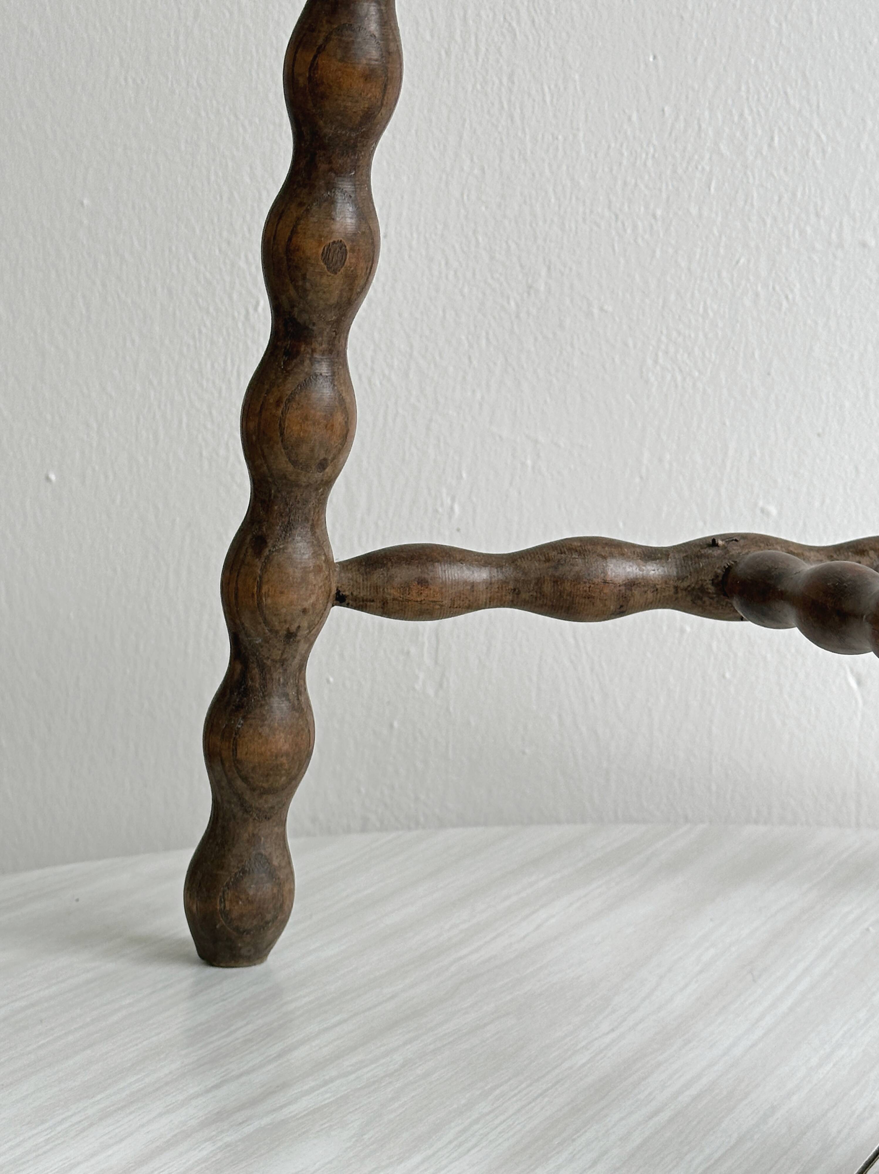 Three-legged demi-lune stool made of turned wood