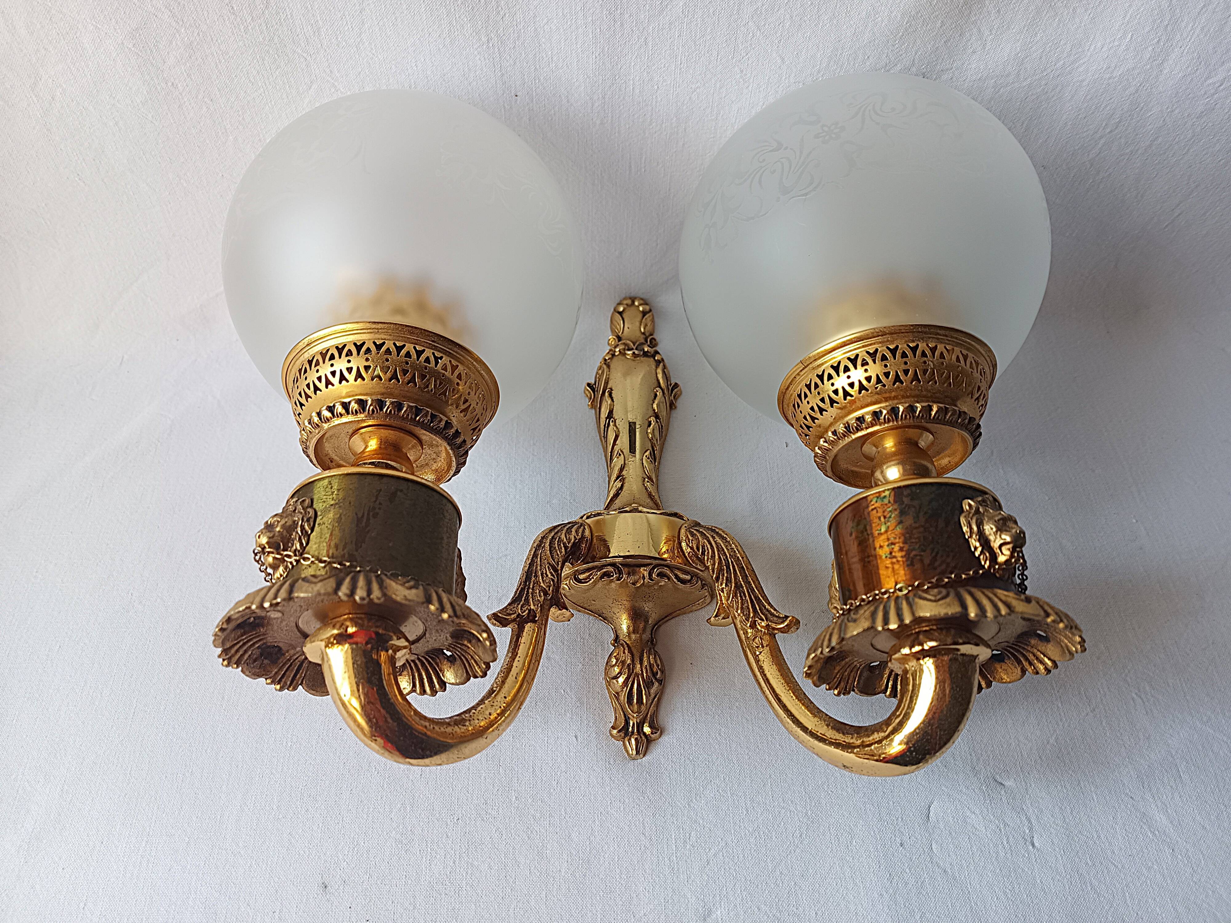 Wall lamp in gilded bronze with a lion's head and engraved globe.