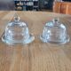 2 transparent glass butter dishes with their matching cloches.