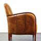 Luxurious cowhide Art Deco design armchair with wooden armrests and cognac-colored leather
