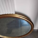 Large and elegant oval gilded mirror with its beveled glass