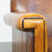 Sheepskin Art Deco design armchair with sleek finish and black piping