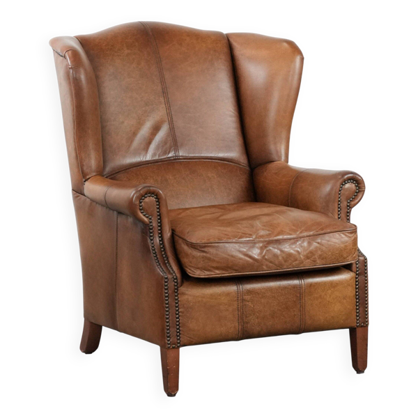 Fauteuil à oreilles couleur cognac de style anglais en cuir de vache.