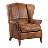 Fauteuil à oreilles couleur cognac de style anglais en cuir de vache.