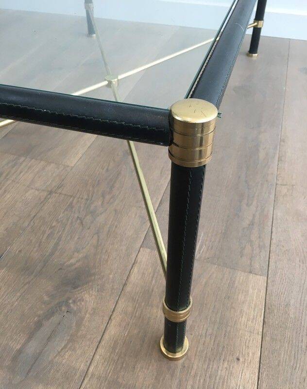 Brass coffee table upholstered in black leather. In the style of Jacques Adnet.