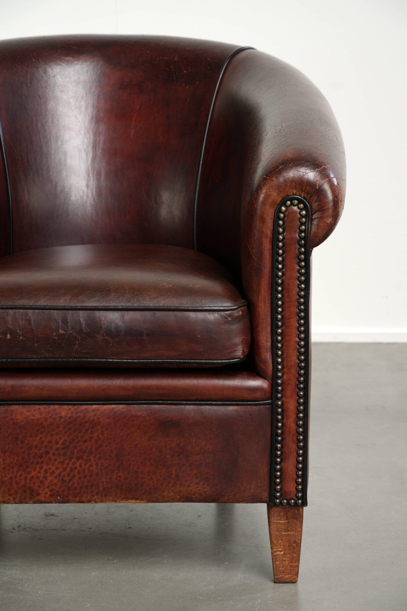 Vintage sheepskin club armchair with decorative nails and black piping