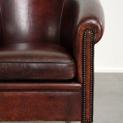 Vintage sheepskin club armchair with decorative nails and black piping