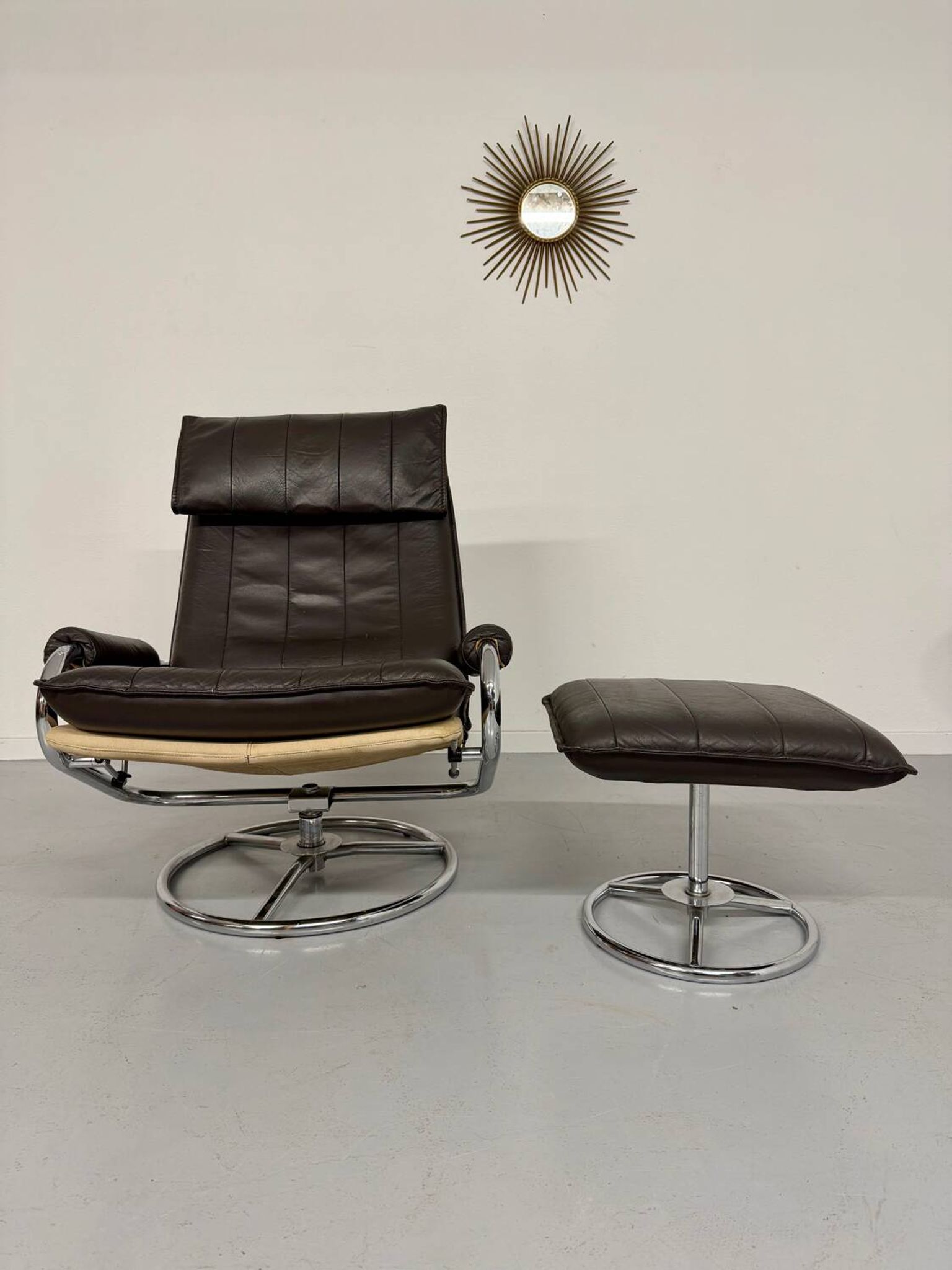 Vintage leather reclining armchair and its 1970s designer ottoman.