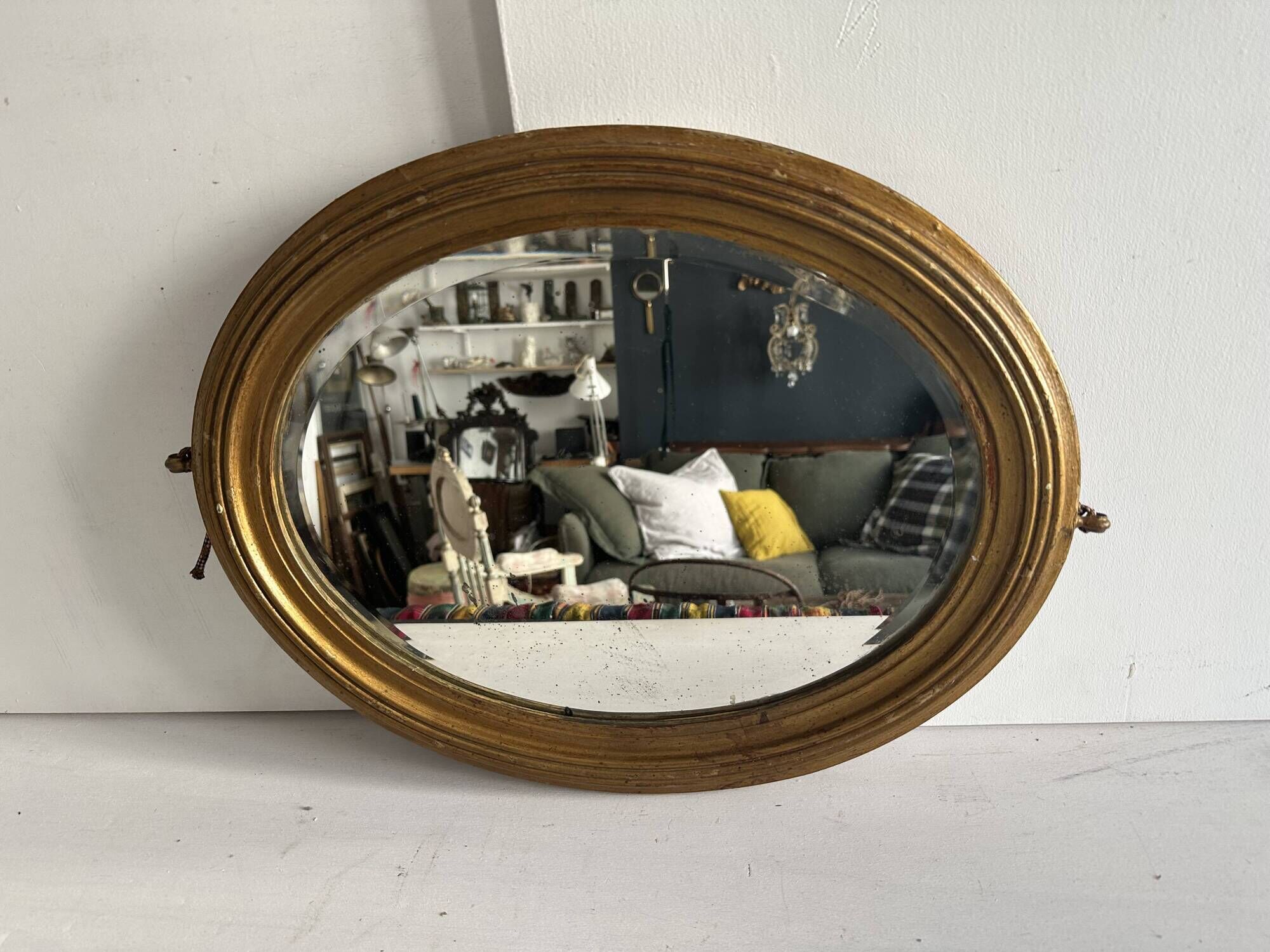 Antique oval mirror in gilded wood, bevelled mercury glass, 19th century.
