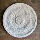 Rosette on white background, decorated with scrolls and beaded frieze ⌀ 61 cm