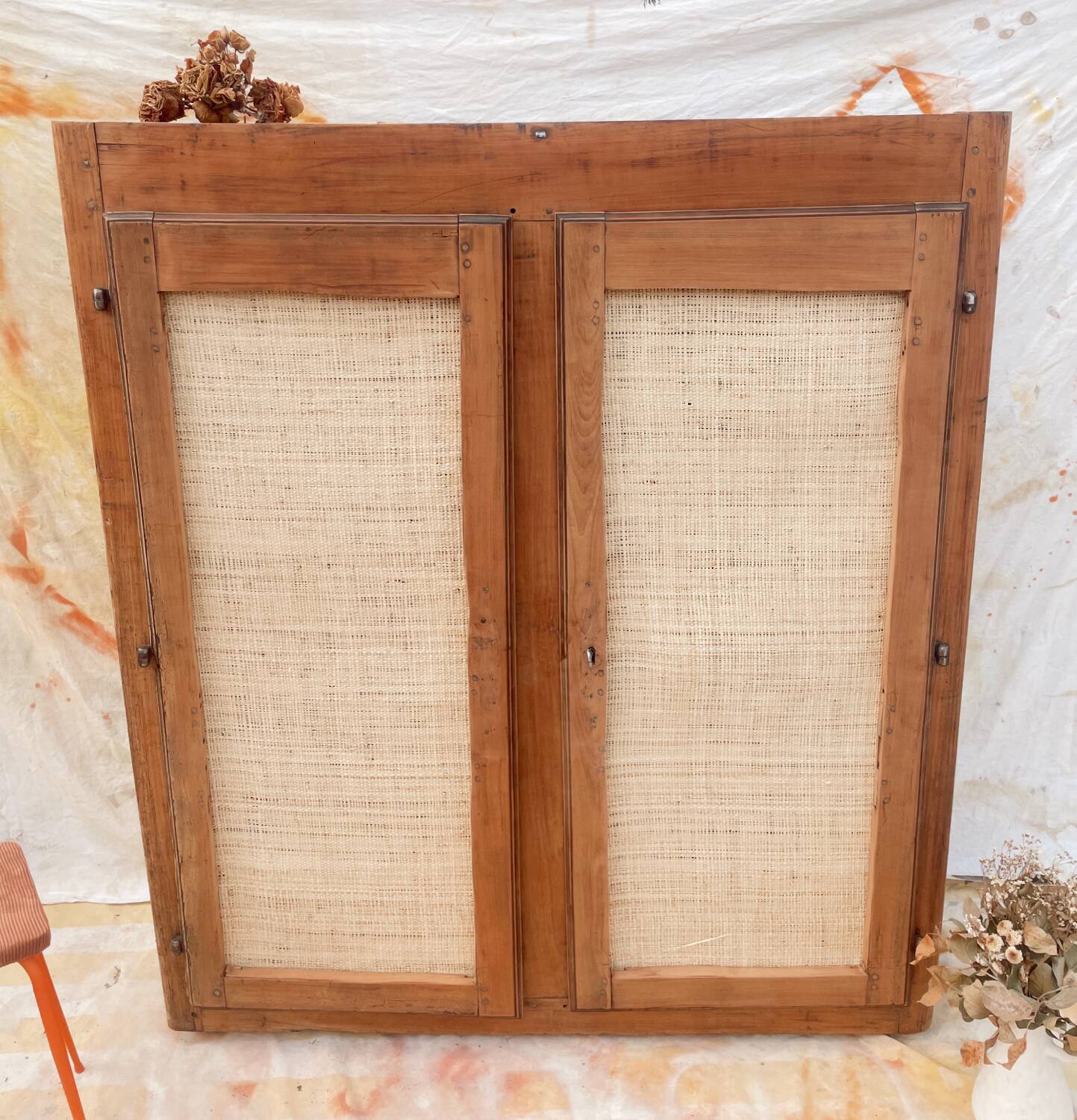 Low cabinet in raw wood and woven raffia.