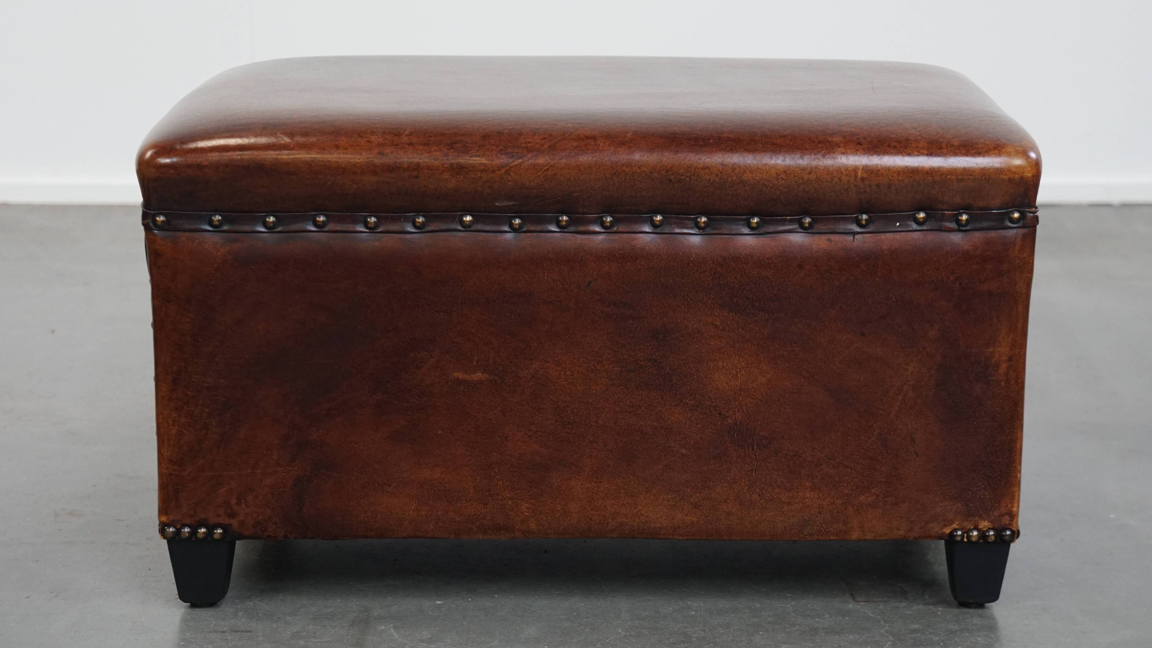 Cognac-colored sheepskin stool with decorative studs