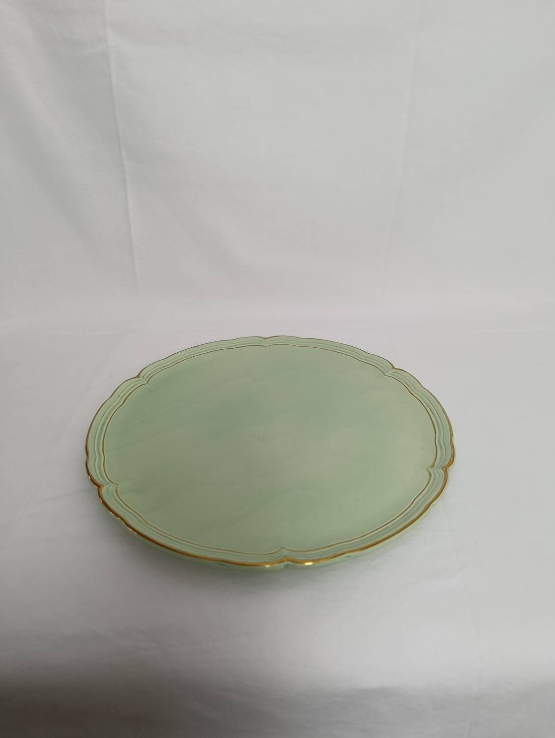 Large pastel green plate with a golden rim.