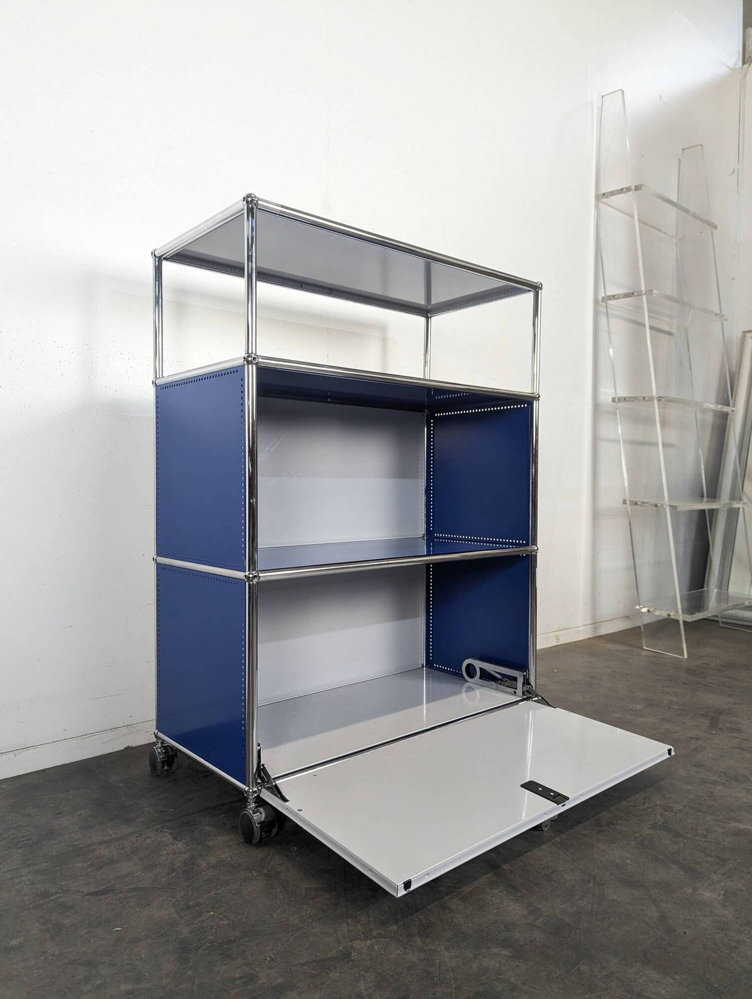 USM Haller furniture in gentian blue and white with a drop-down door on wheels.