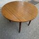 Round kitchen table with extendable leaves in dark wood.