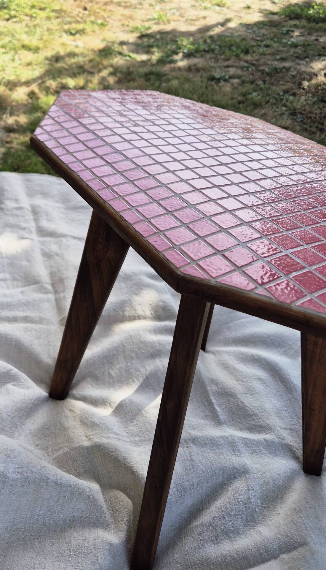 Small Scandinavian side table with wood and pink tiles, with tapered legs.