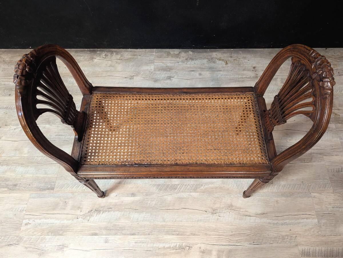 Louis XVI bench in walnut with cane seating.