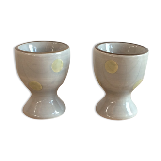 Two beige/greige ceramic egg cups with large yellow polka dots