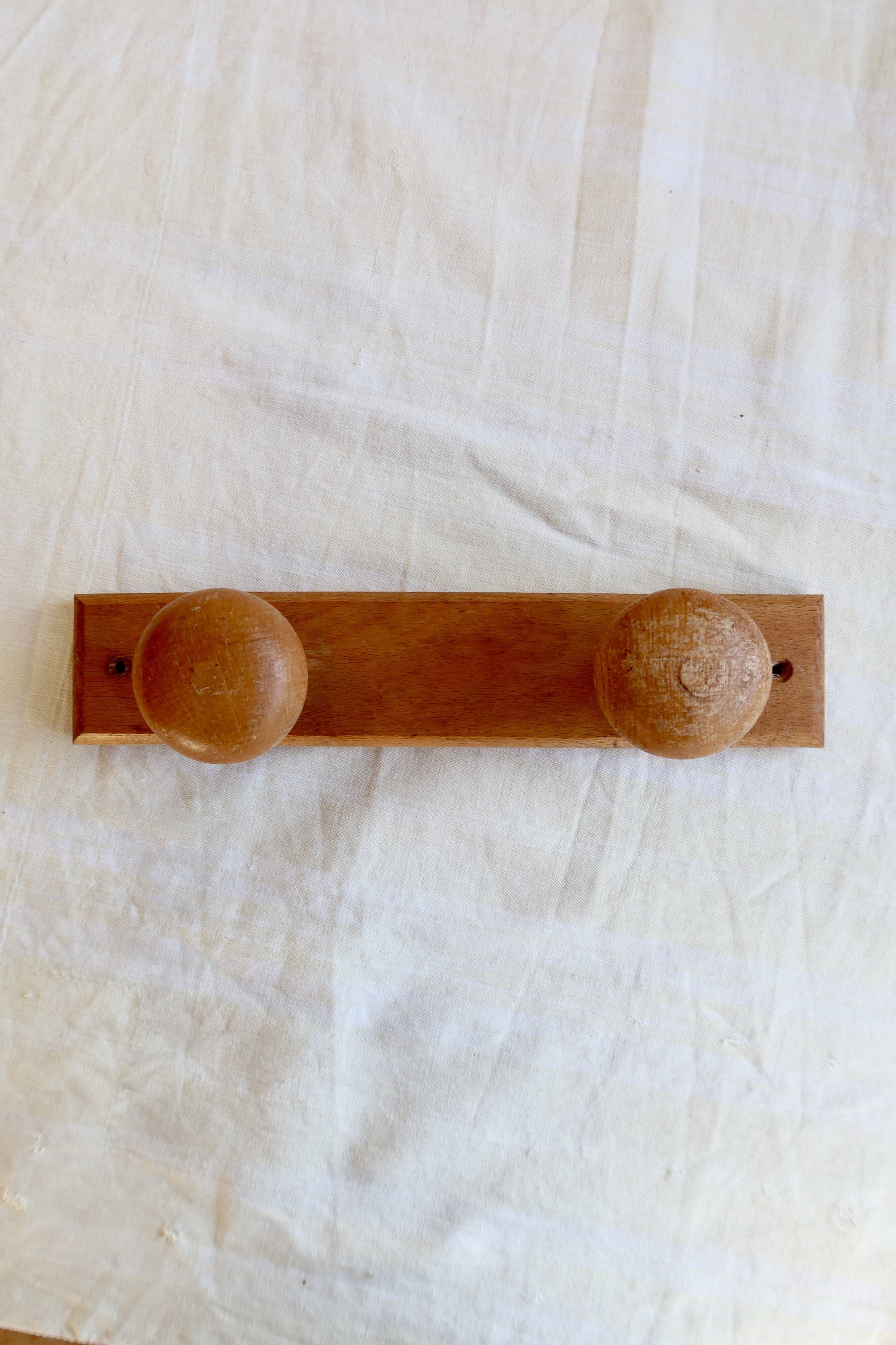 Vintage wooden coat rack with two round hooks.