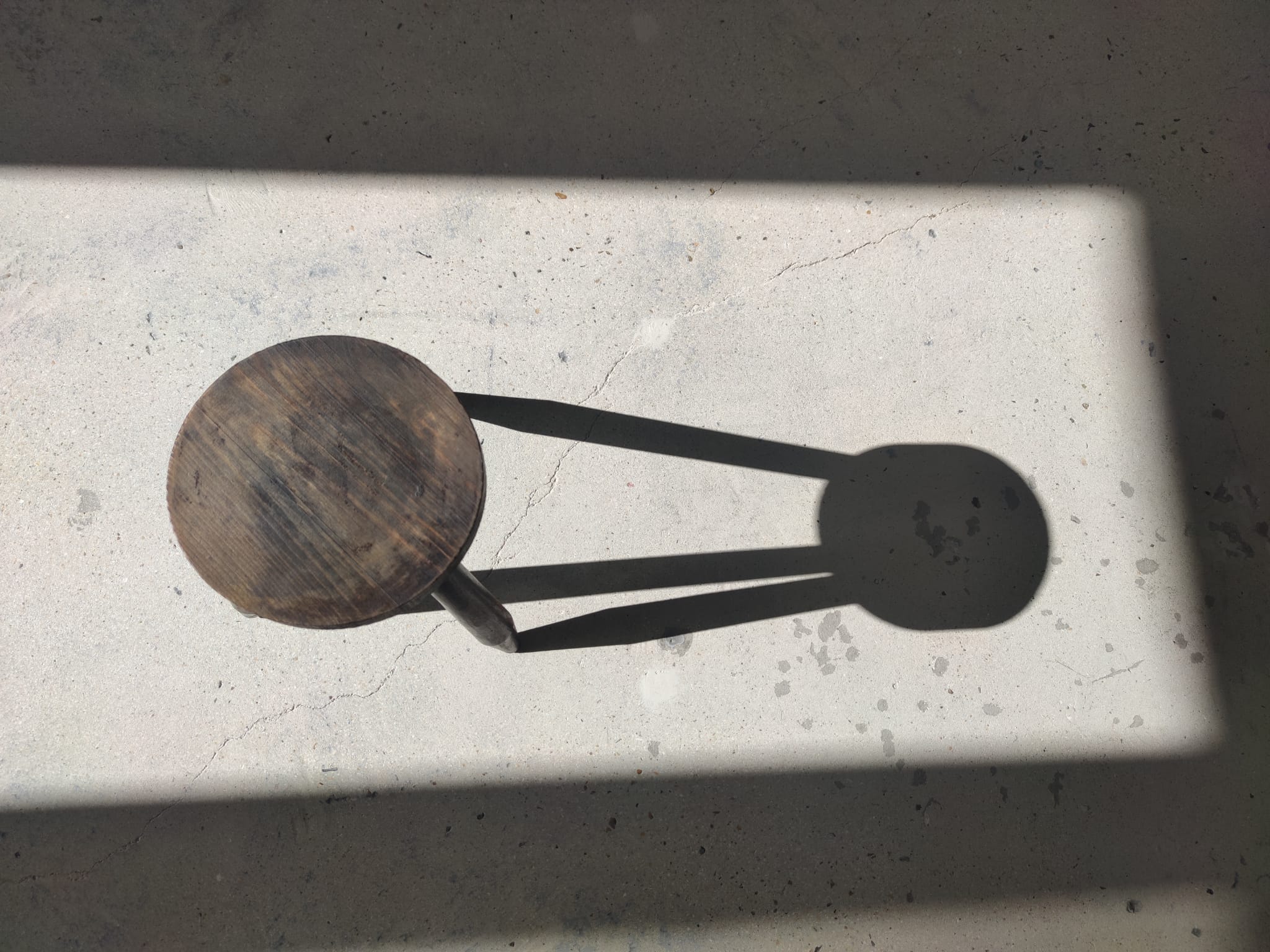 Small brutalistic tripod stool in dark wood tapered feet circular seat