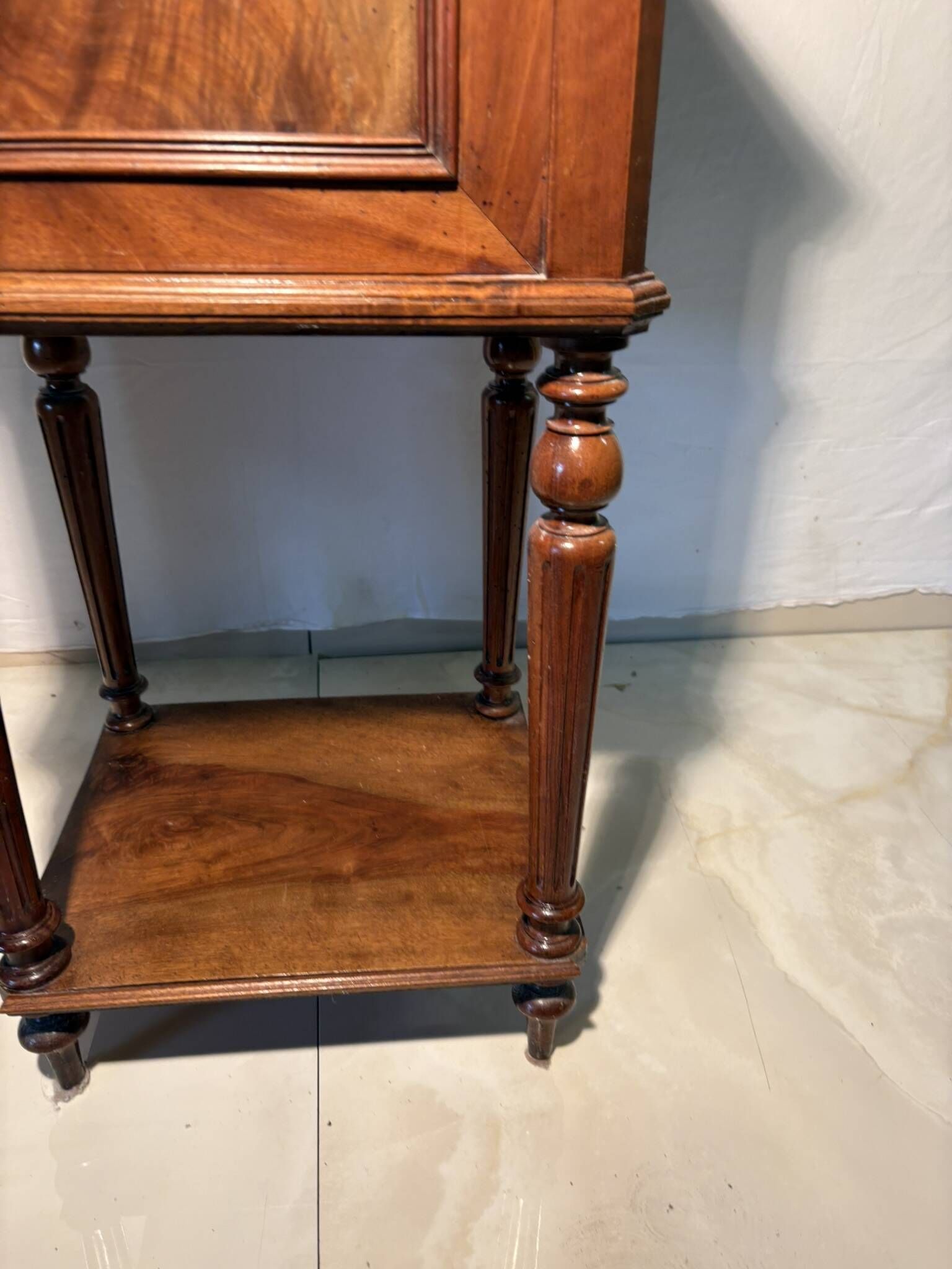 Antique wooden bedside table with turned legs.