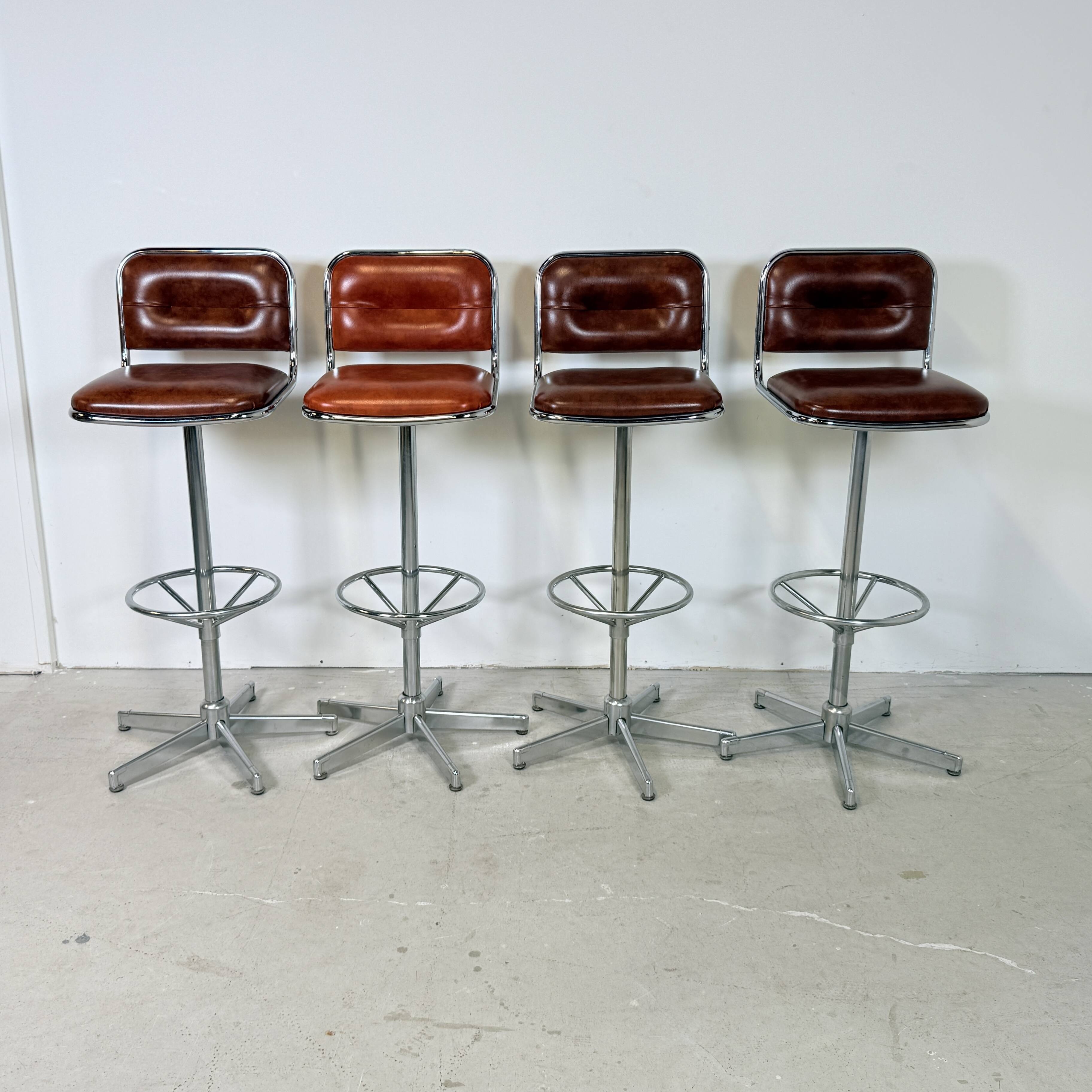 1970s chrome bar stools with cognac-colored faux leather upholstery