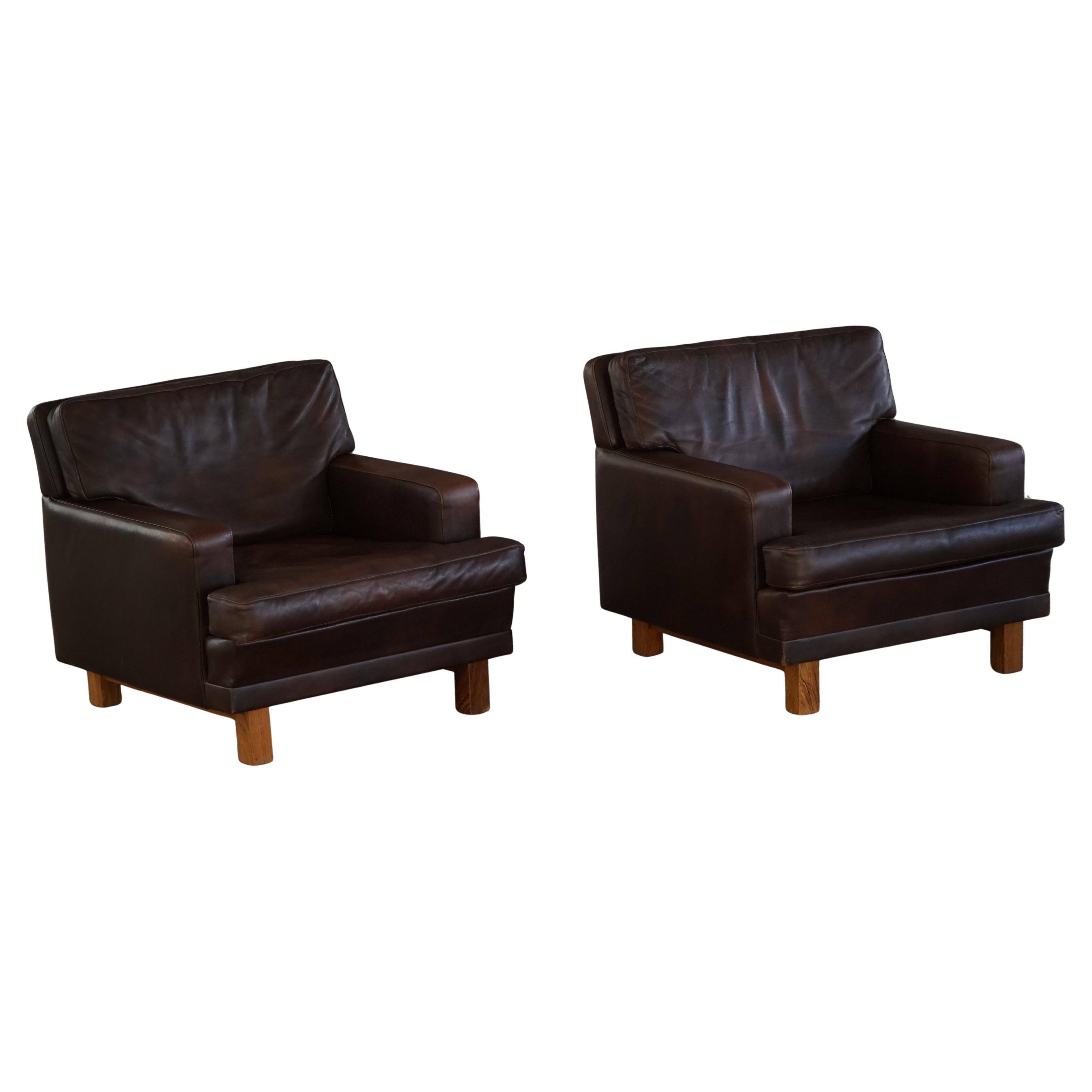 Pair of modern Danish lounge chairs in dark brown leather and rosewood, 1960s.