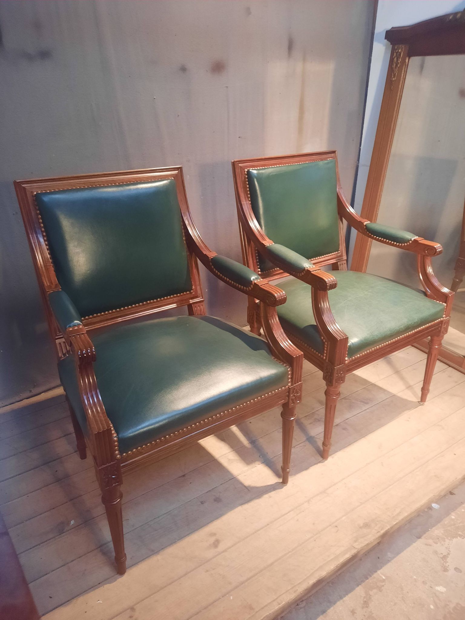 Pair of Louis XVI style armchairs upholstered in green leather.
