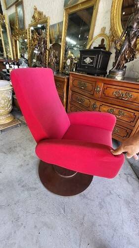 Old cinema chair with a red reclining seat.