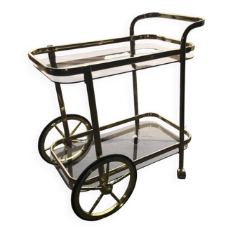 Two-tier bar cart in gold-plated brass with transparent glass shelves, yellow finish.