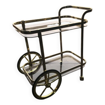 Two-tier bar cart in gold-plated brass with transparent glass shelves, yellow finish.