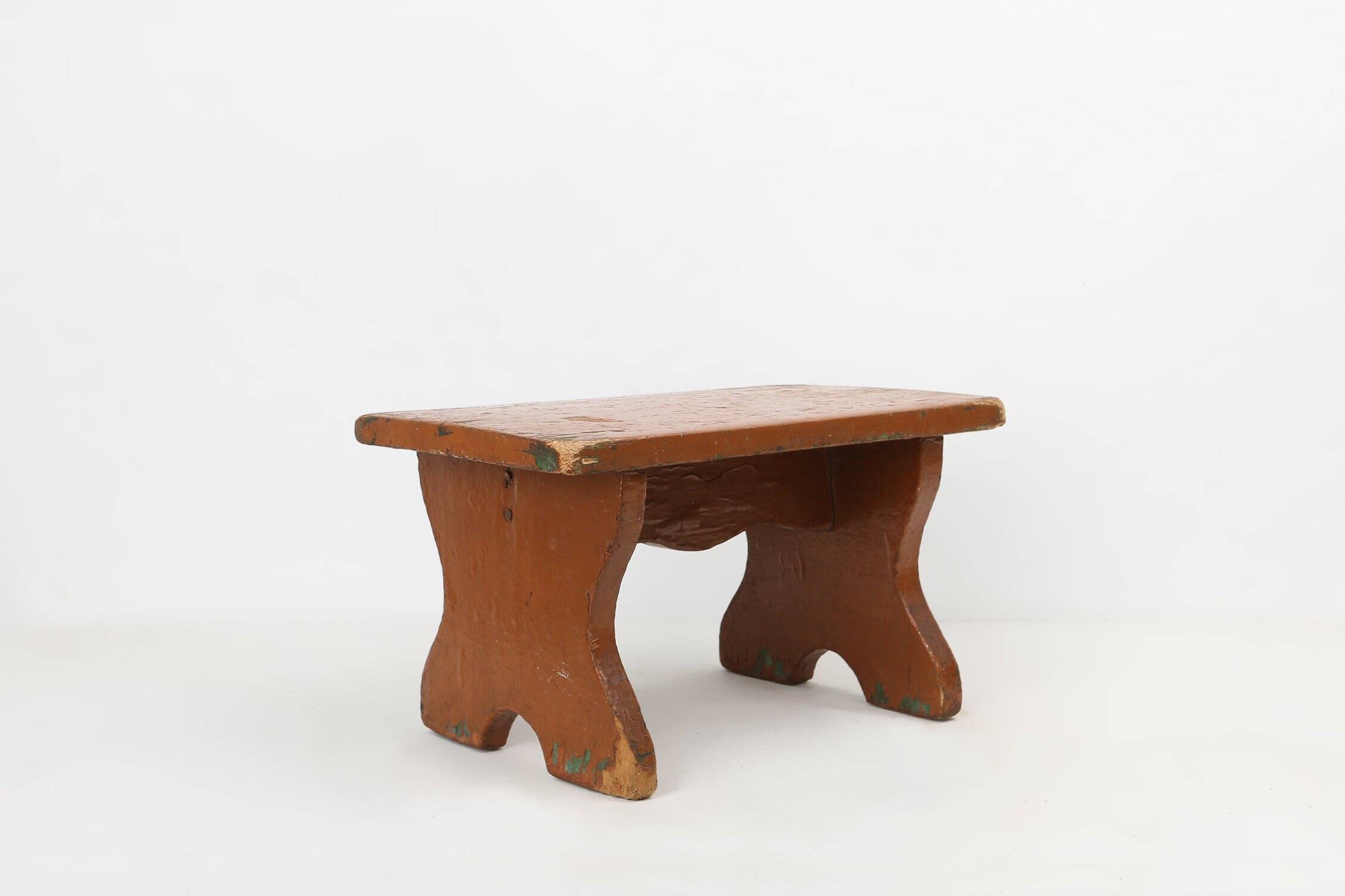 Tabouret bas rustique français en bois peint en terre cuite, années 1890.