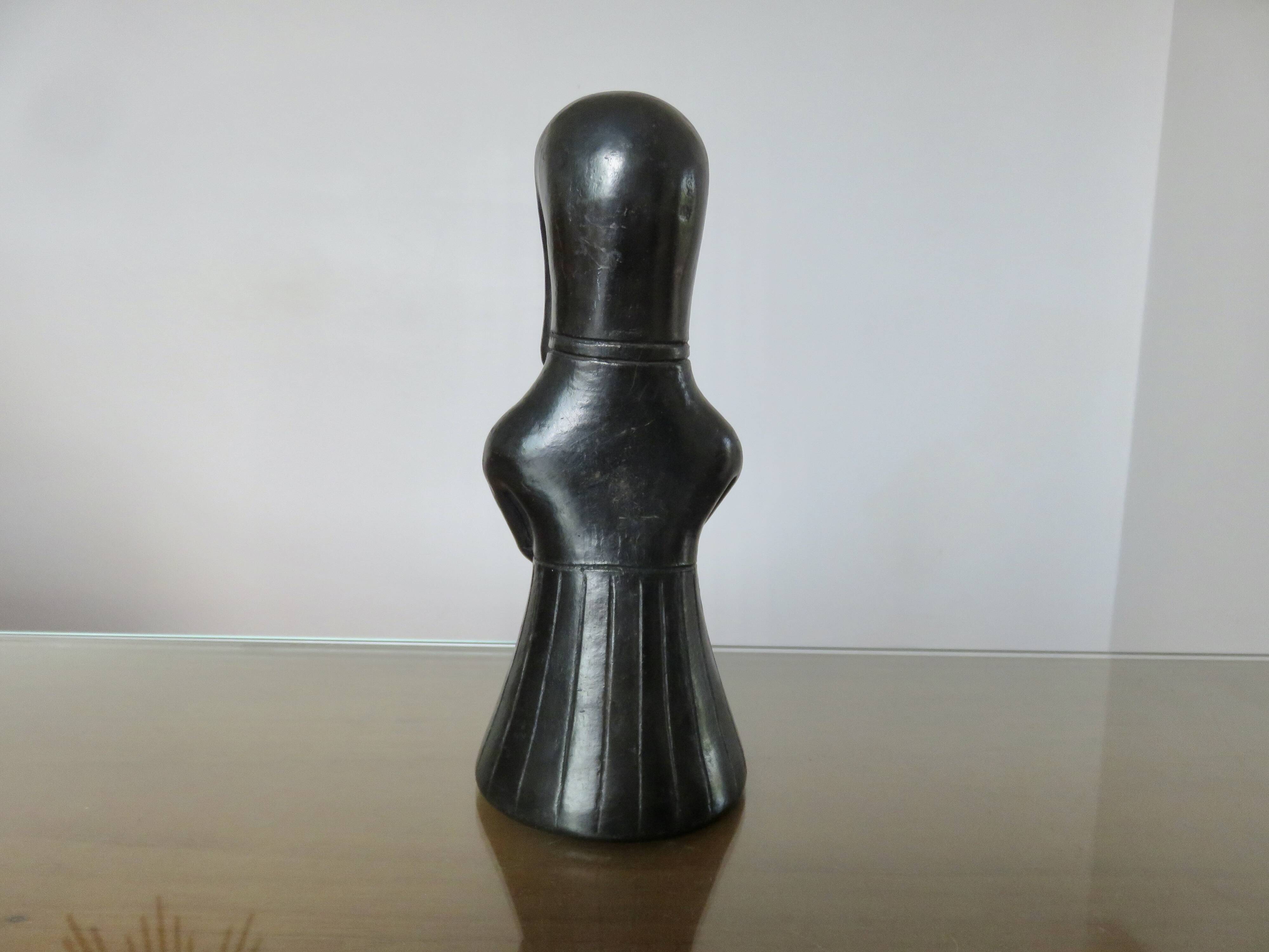 Matte black ceramic sculpture representing a female tribal figure.