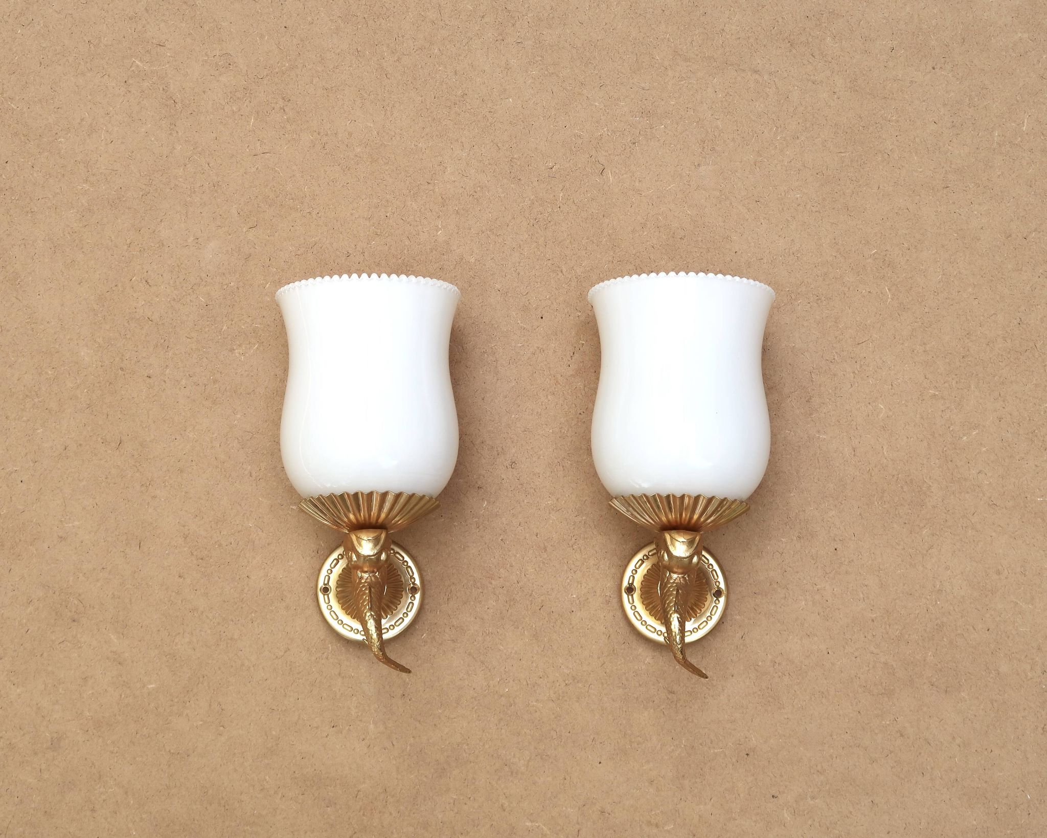 Pair of gold metal and opaque glass wall lights adorned with fish from the 1950s.