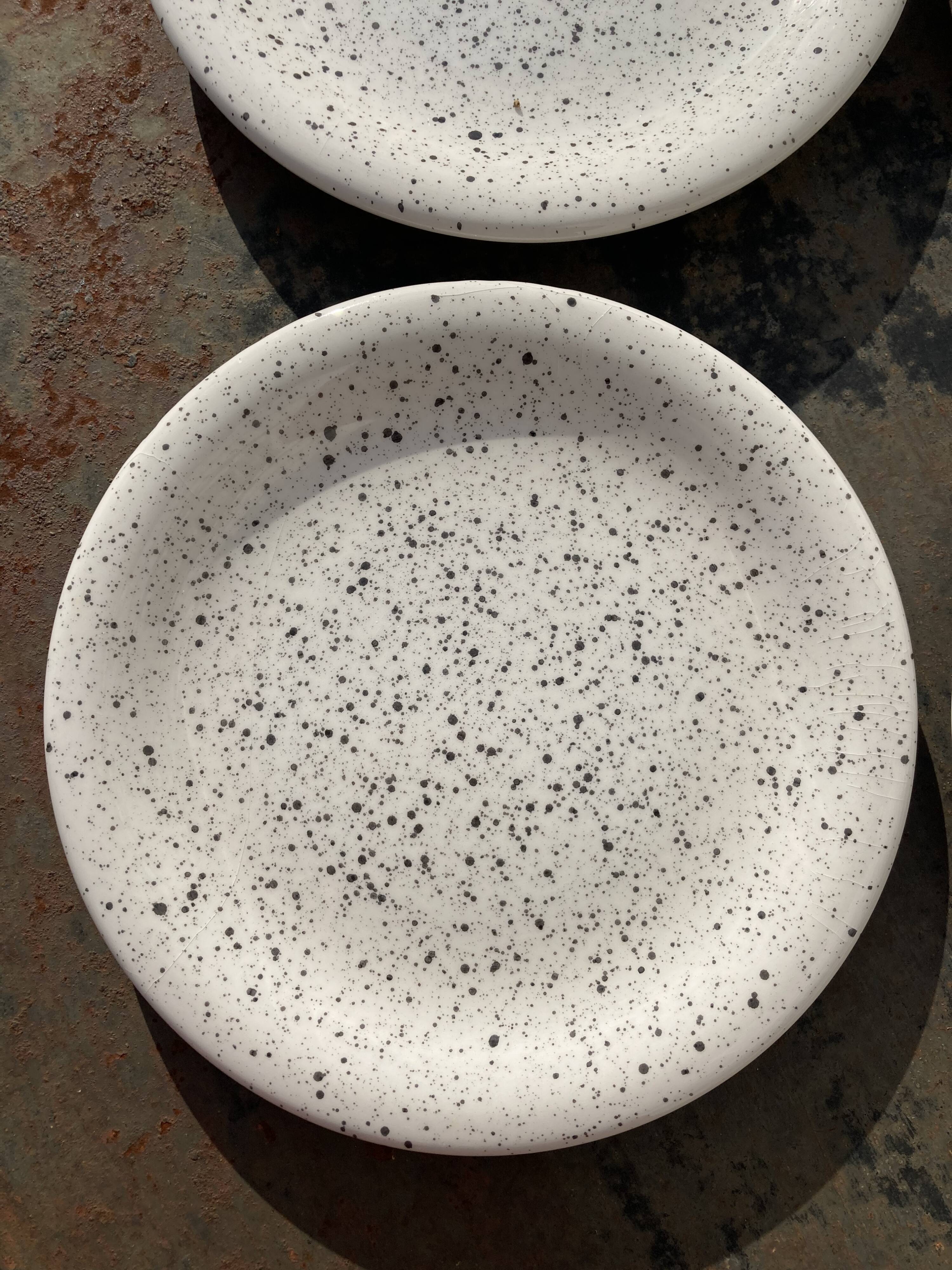 4 black speckled dessert plates on a vintage white background