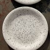 4 black speckled dessert plates on a vintage white background