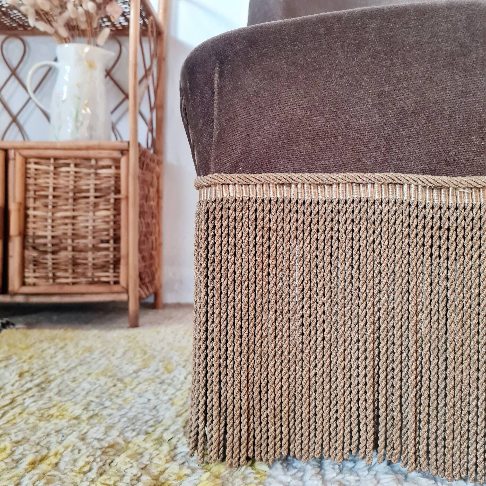 Brown velvet crapaud armchair with fringes and sculpted legs.