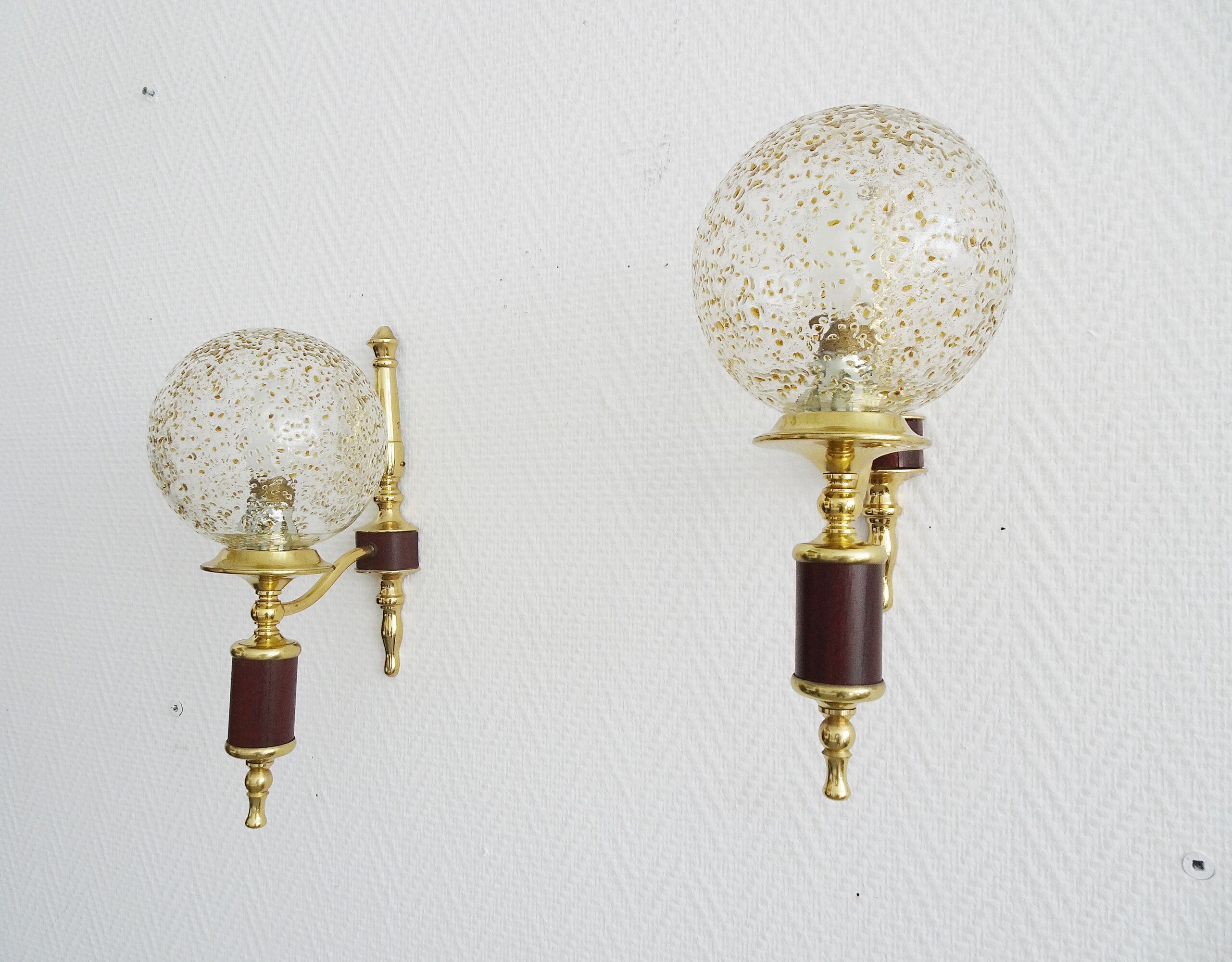 Golden wall lamps with round glass shades and teak veneer