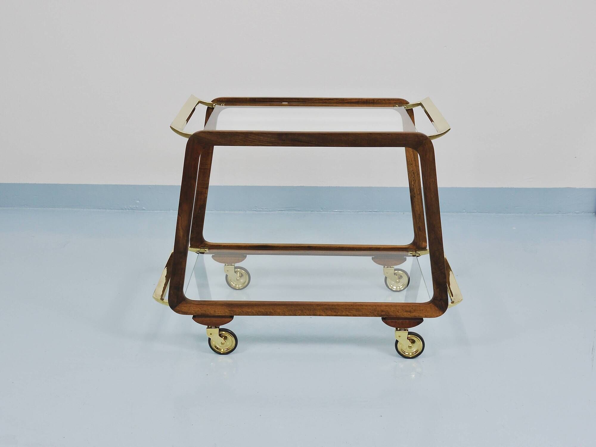 May include: A mid-century modern bar cart with a dark wood frame and two c
