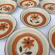 Set 11 plates 1970 Revernay Sarreguemines orange and brown on sandstone background