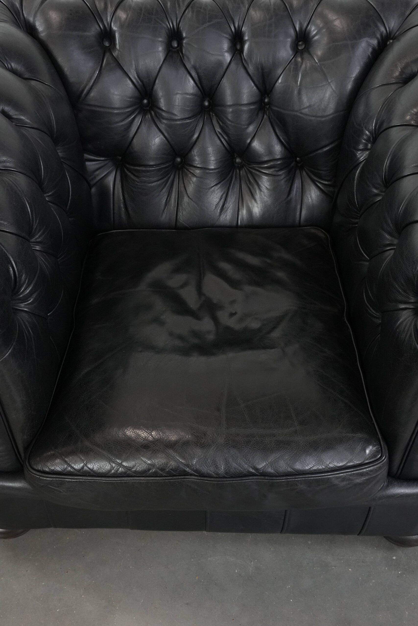 Ensemble composé d'un canapé chesterfield noir, d'un fauteuil et d'un pouf.