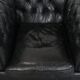 Ensemble composé d'un canapé chesterfield noir, d'un fauteuil et d'un pouf.