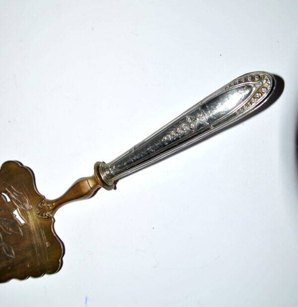 Antique silver-plated pie server with a brass blade decorated with roses.