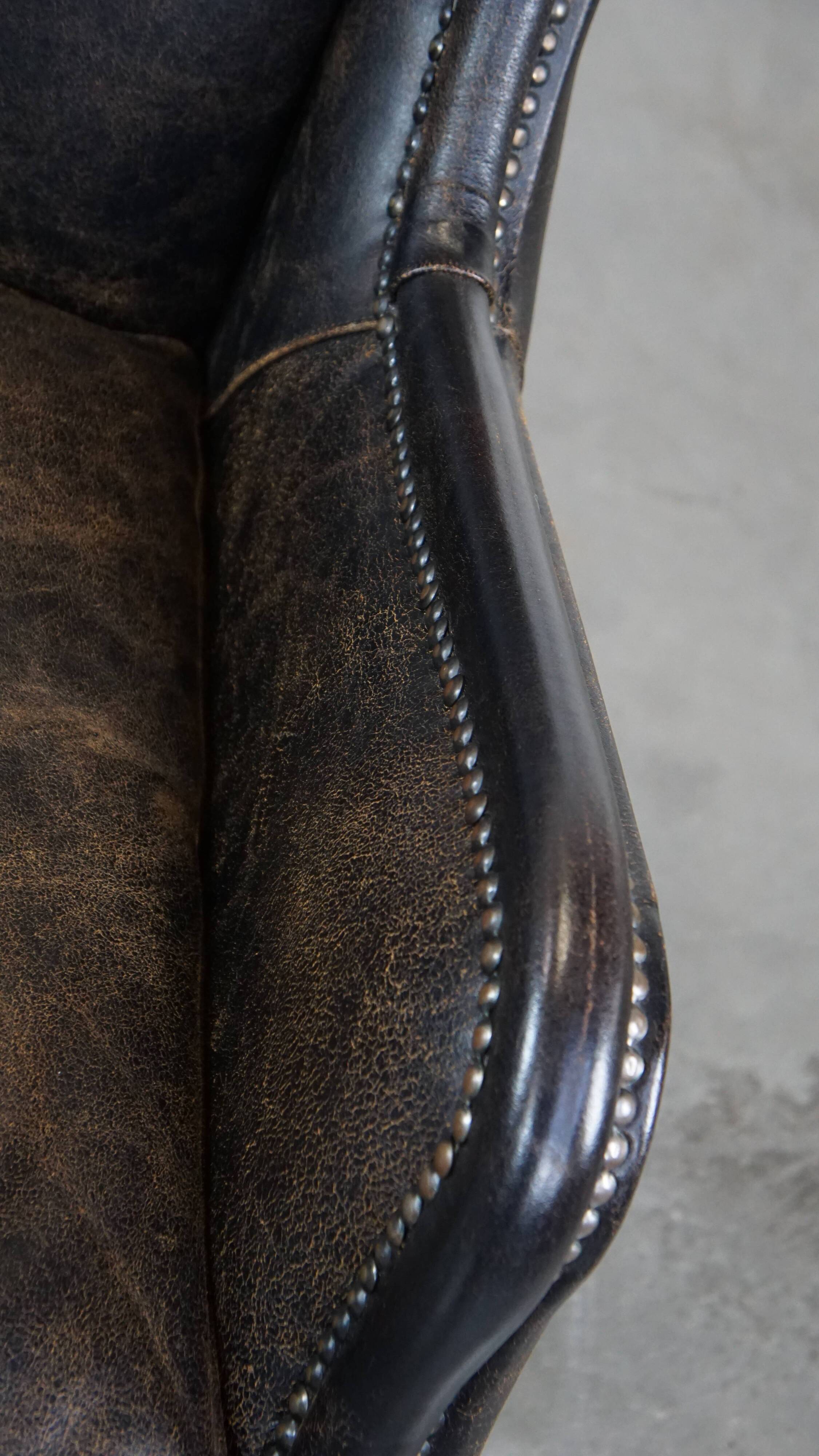 Black cow leather armchair in industrial style finished with decorative nails