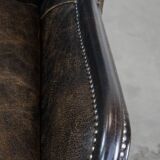 Black cow leather armchair in industrial style finished with decorative nails