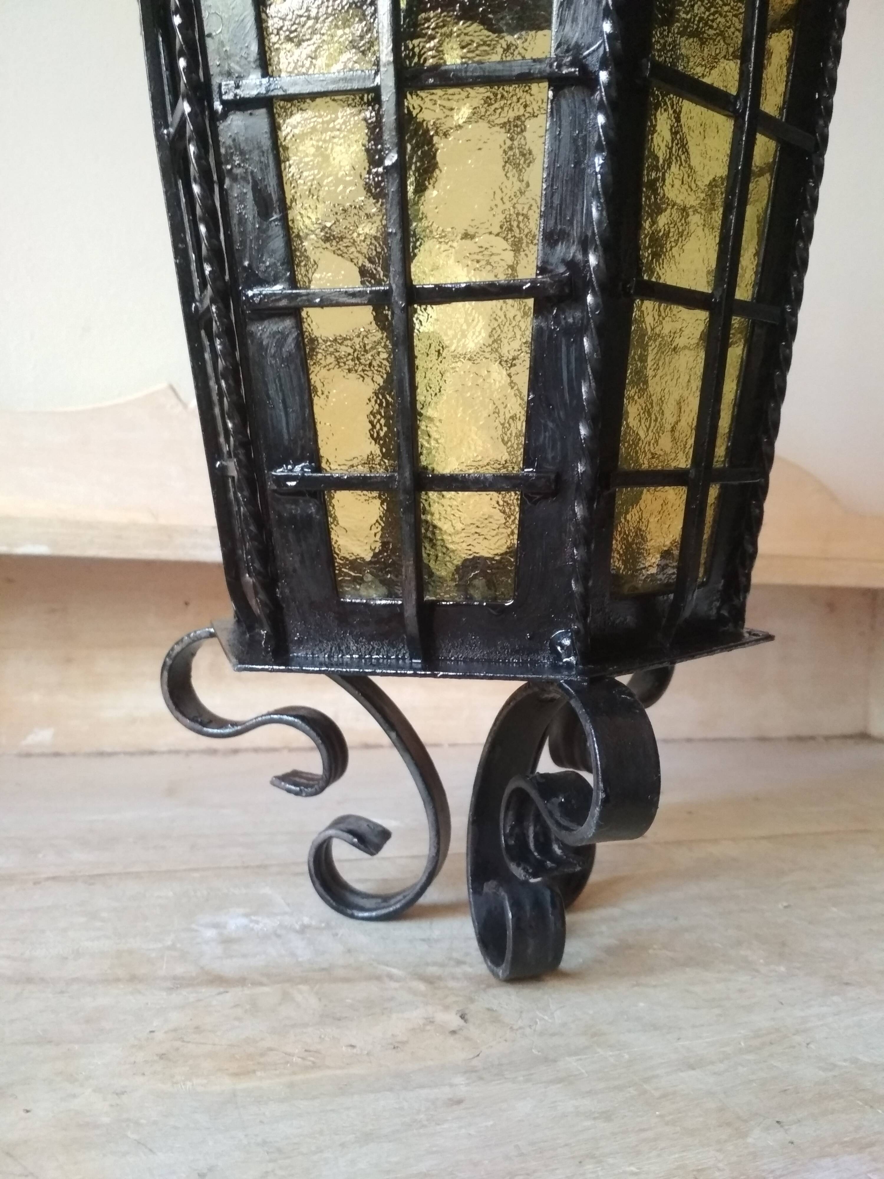 Large hanging lantern in wrought iron and opaque yellow-orange windows