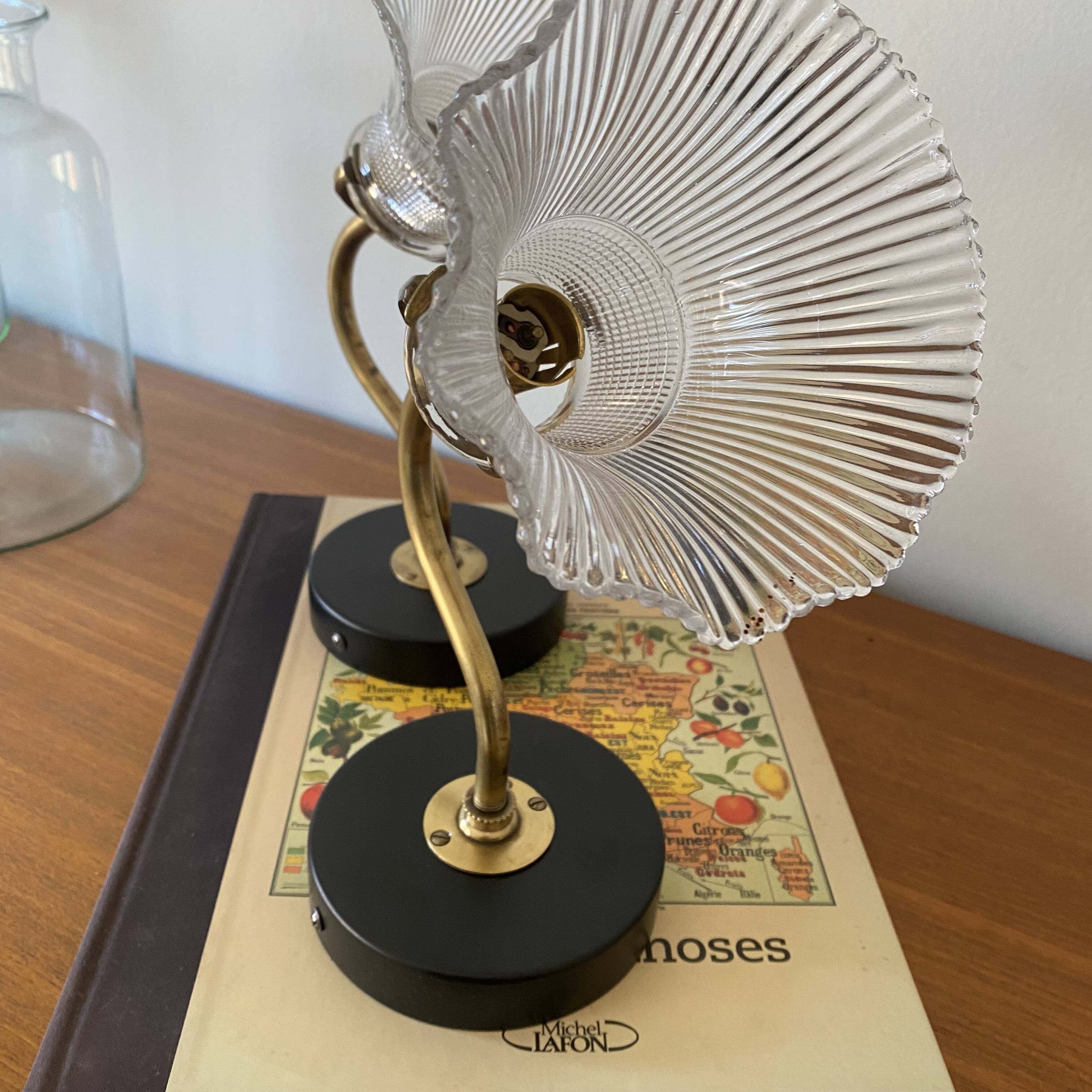 Pair of brass swan neck wall lights with transparent glass shades.