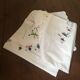 Oval tablecloth and napkins in white cotton embroidered in color