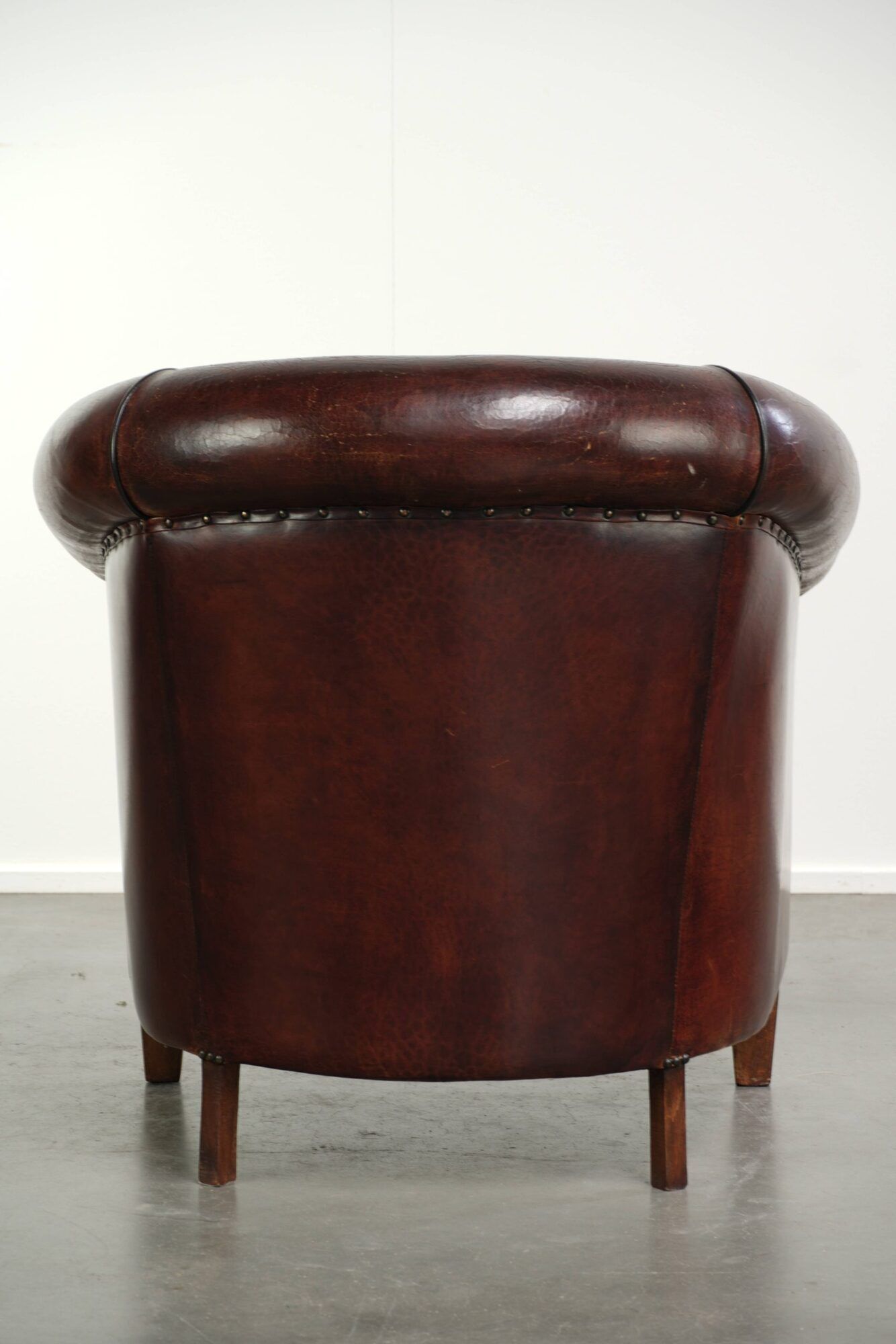Vintage sheepskin club armchair with decorative nails and black piping