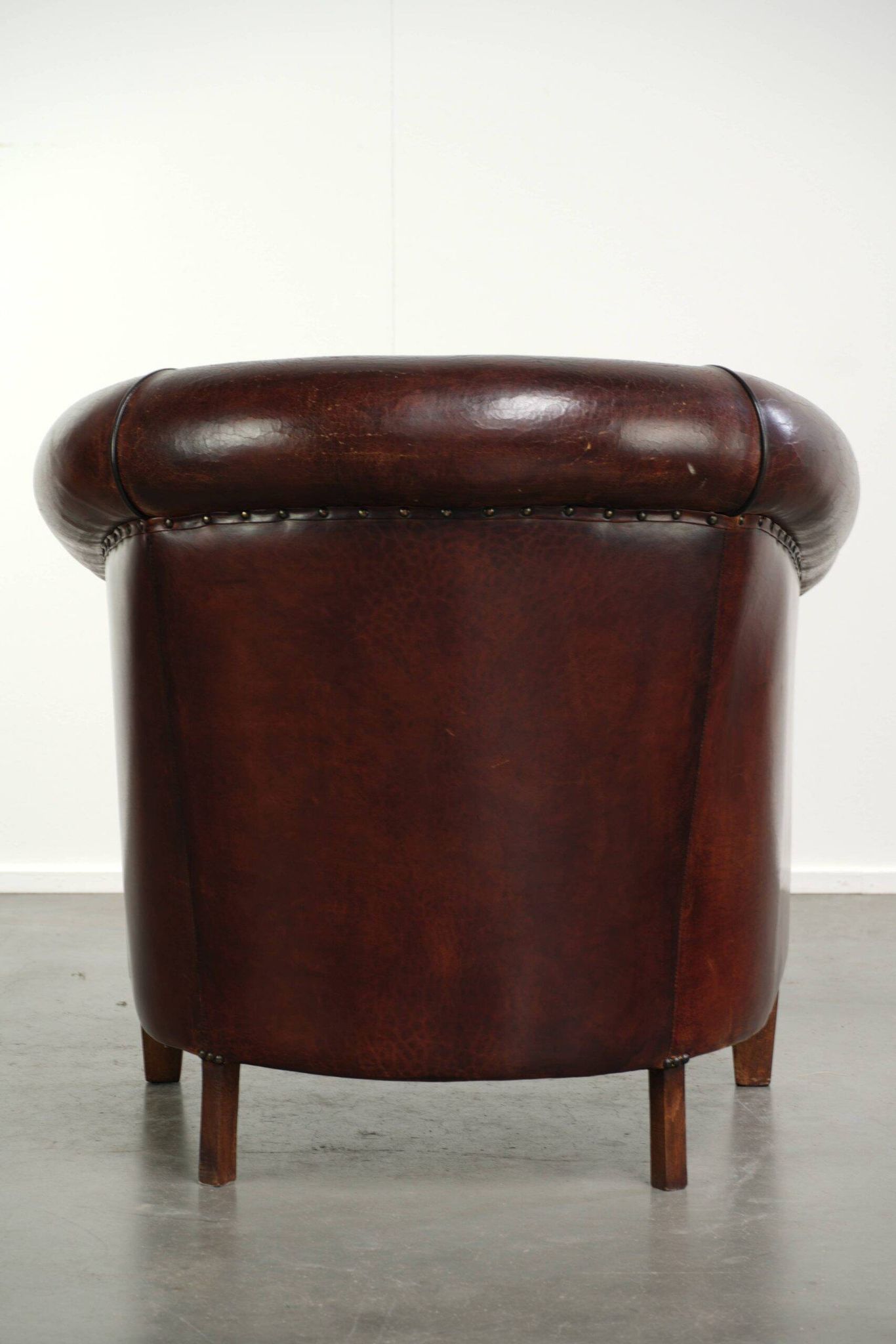 Vintage sheepskin club armchair with decorative nails and black piping